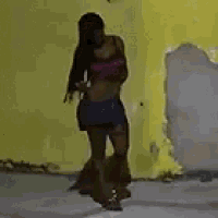 a woman in a pink top and shorts is standing in a room .