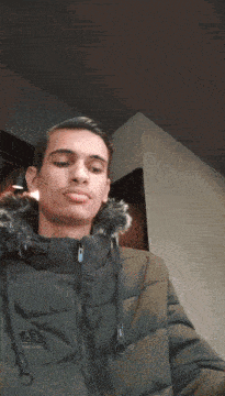 a young man wearing a green jacket with a fur hood