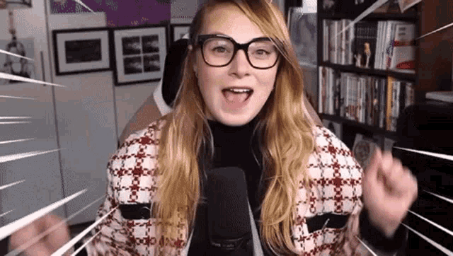 a woman wearing glasses is talking into a microphone