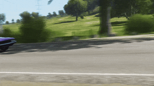 a purple car is driving down a road next to a park