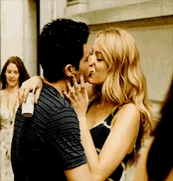 a man and woman are kissing in front of a crowd .