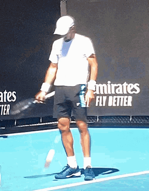 a man is holding a tennis racquet on a tennis court in front of an emirates fly better banner