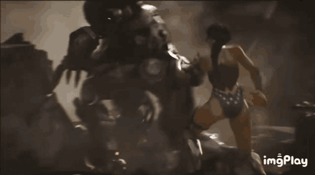 a woman in a bikini is fighting a robot in a dark room .