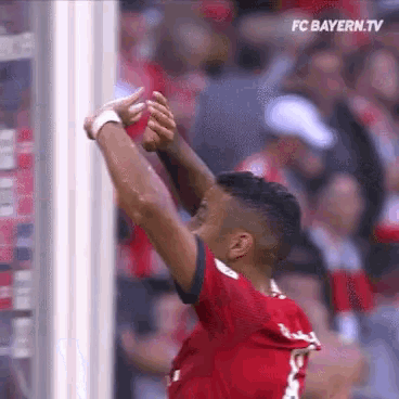 a soccer player in a red shirt is raising his arms in the air