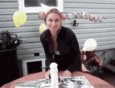 a woman is standing in front of a table with a spray bottle and balloons behind her ..