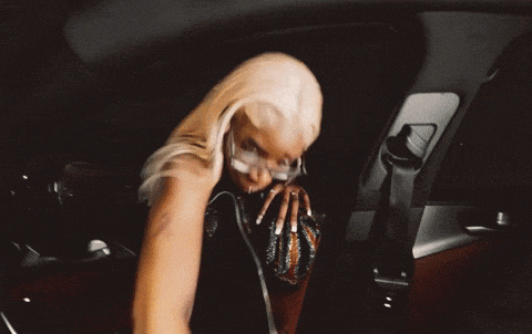 a woman with blonde hair is sitting in a car with headphones on .