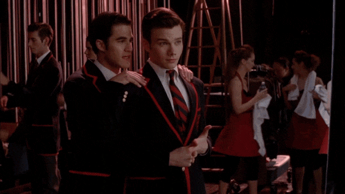 two men in suits and ties are standing next to each other with one pointing