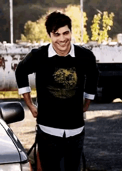 a man wearing a black sweater with a lion on it is smiling
