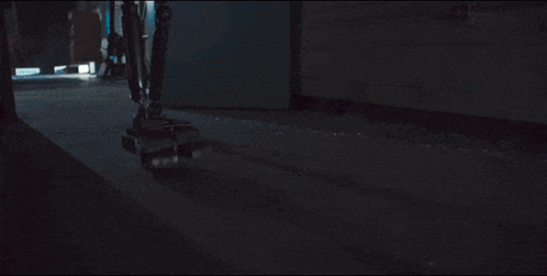 a person is standing in a dark room with a skateboard on the floor