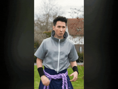 a man with a purple rope around his waist looks at the camera
