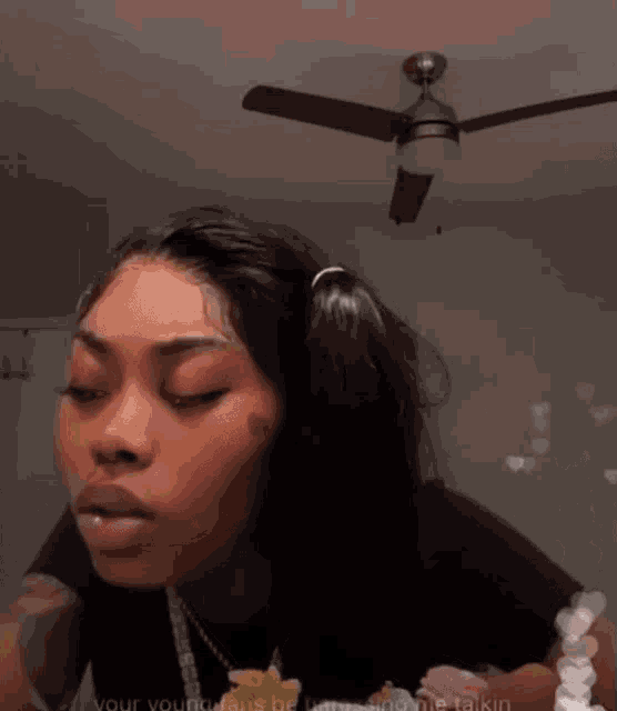 a woman is standing in front of a ceiling fan and looking at the camera .
