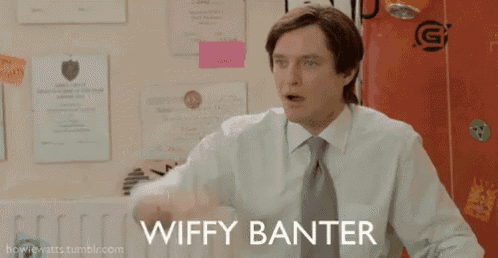a man in a suit and tie is standing in front of a red door and says wiffy banter .