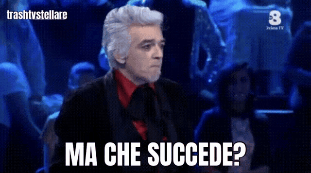 a man in a red shirt and black suit says " ma che succede "