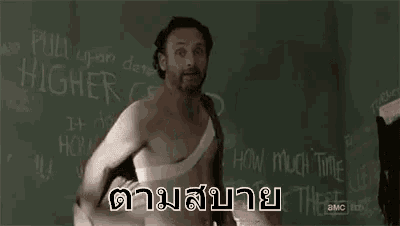 a shirtless man with a bandage on his chest is standing in front of a blackboard in a room .