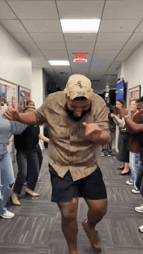 a group of people are dancing in a hallway with a man wearing a white sox hat