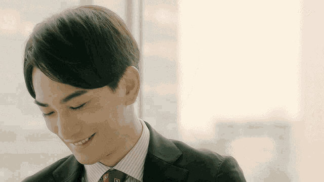 a man wearing a suit and tie is smiling with his eyes closed