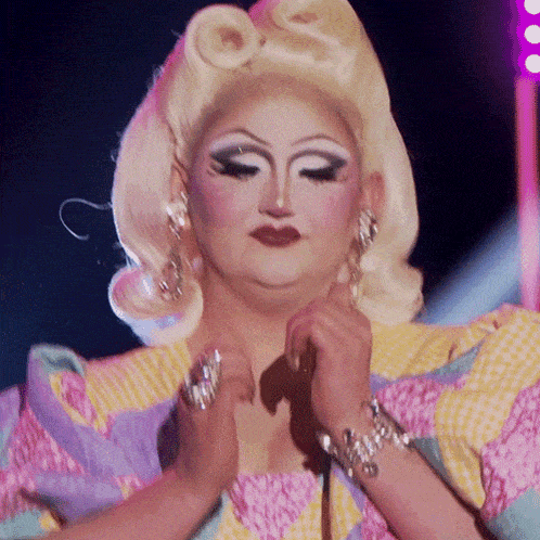 a drag queen is wearing a colorful striped dress and bracelets