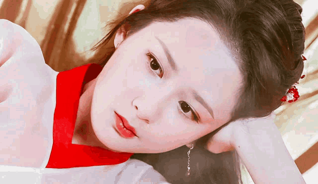 a close up of a woman 's face with a red collar and earrings