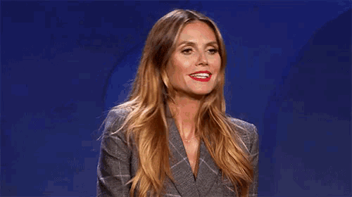a woman with long hair and red lipstick is making a funny face and saying sigh .