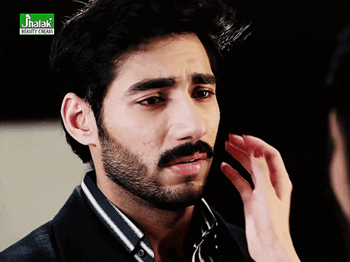 a man with a beard is being touched by a woman in front of a green banner that says jitak beauty cream