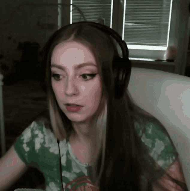 a girl wearing headphones and a tie dye shirt is sitting in front of a window