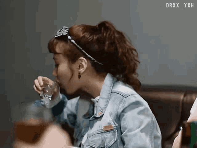 a woman in a denim jacket drinking from a glass with the watermark drxx_yxh