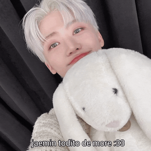 a young man with white hair is holding a white stuffed animal with the caption jaemin todito de more 33
