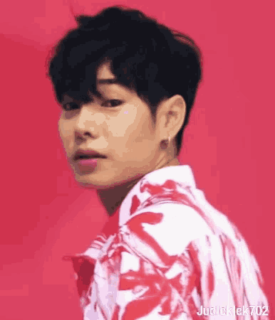 a young man is wearing a red and white shirt and earrings .