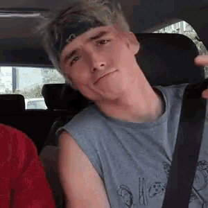 a young man wearing a headband is sitting in a car .