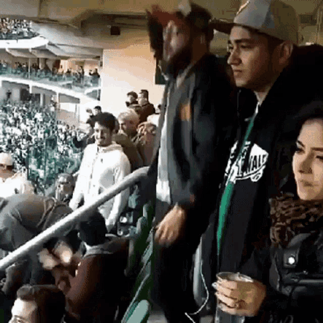 a group of people in a stadium one of whom is wearing a jacket that says ' vans ' on it