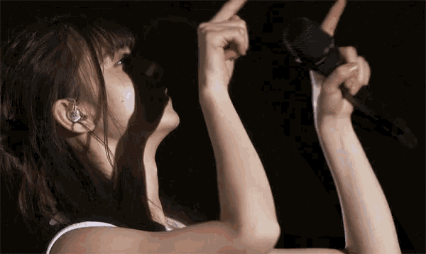 a woman is singing into a microphone with her hands in the air .