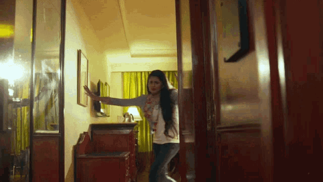 a woman in a white shirt is standing in a room
