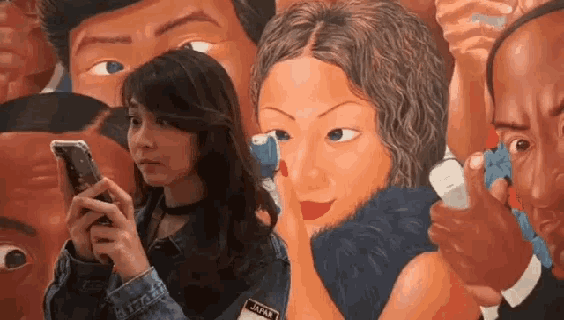 a woman is looking at her phone while standing in front of a painting that says ' japan ' on it