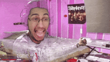 a slipknot poster hangs on the wall behind the man