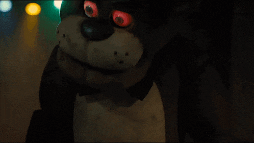 a stuffed animal with red eyes is standing in the dark
