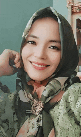a woman wearing a scarf with a brooch around her neck is smiling