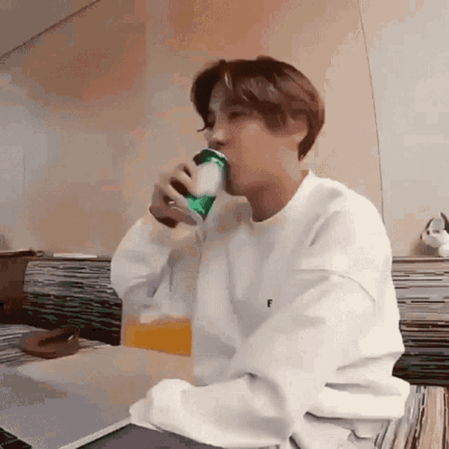 a young man is drinking a can of soda from a green can .