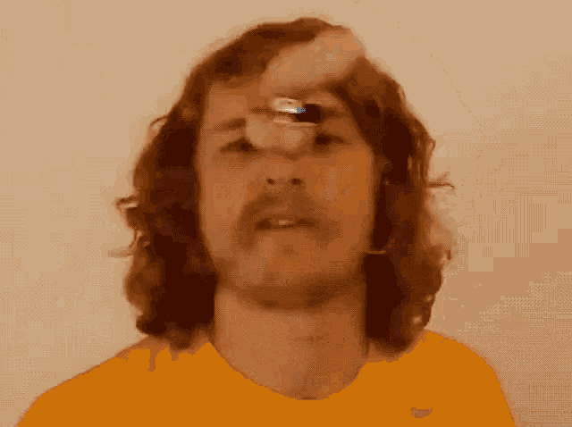 a man with long hair and a mustache is wearing an orange shirt with the word nike on it