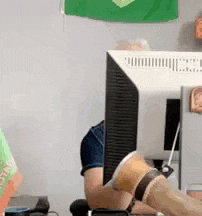 a man is sitting in front of a computer monitor with his legs crossed .