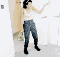 a woman in a tank top and polka dot pants is dancing in a room