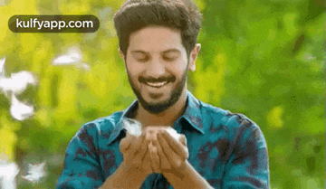 a man with a beard is smiling while holding a bird in his hands .