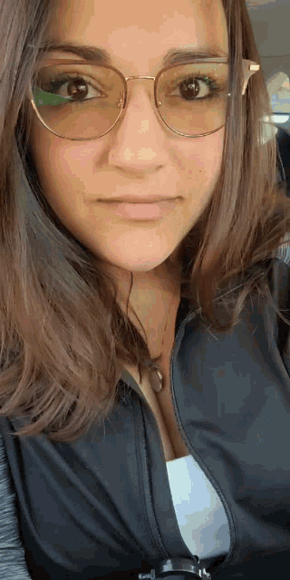 a young woman wearing glasses and a black jacket
