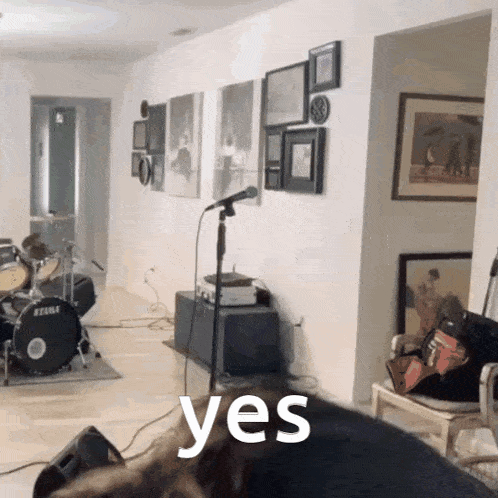 a room with a drum set and a microphone and the word yes on the bottom