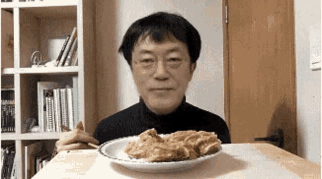 a man is sitting at a table with a plate of food on it .