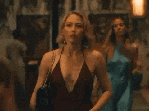 a woman in a red tank top is walking down a street with other women .