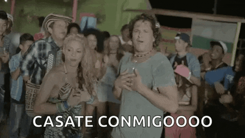 a man and a woman are dancing in front of a crowd of people in a video .