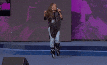 a woman singing into a microphone on stage
