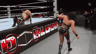 two women wrestling in a ring with a sign that says blood on it