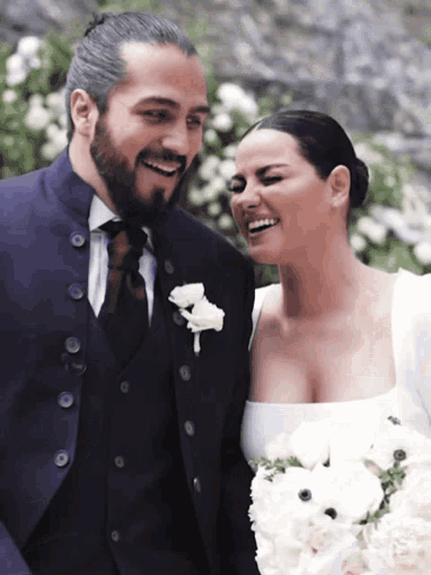 a man in a suit and tie and a woman in a white dress smile for the camera
