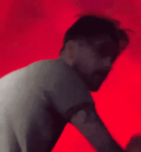 a blurry picture of a man with a beard dancing on a red background .